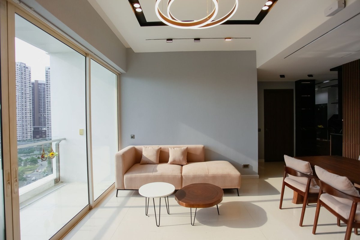 Modern condo living room with beige sofa, ring chandelier, and balcony view of high-rises